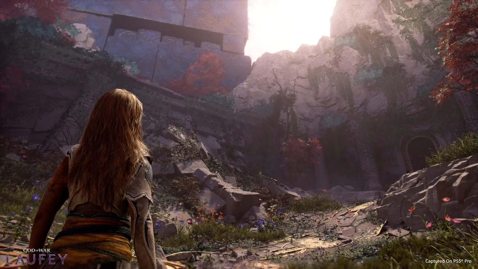 Faye seen from behind overlooking a misty canyon filled with ancient stone ruins and red-leafed trees
